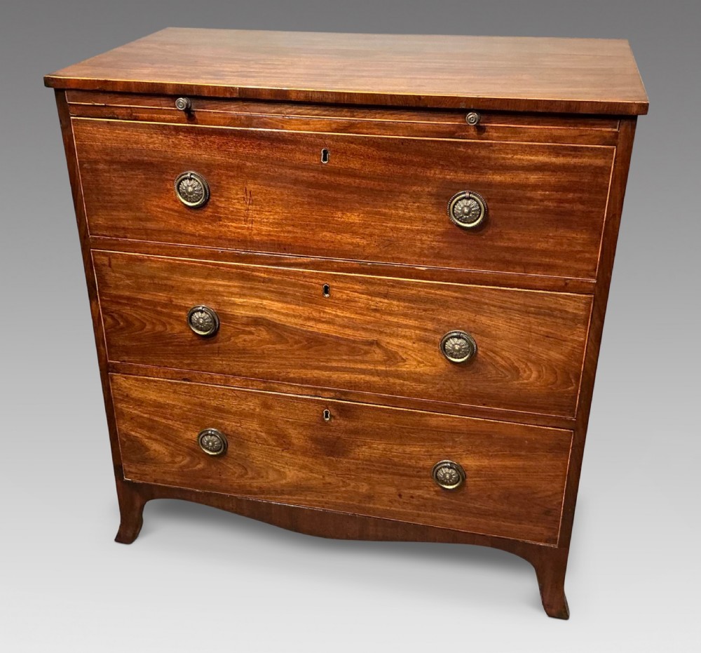A Georgian mahogany chest of drawers featuring three graduated drawers, a pull-out brushing slide, brass rosette handles, and splayed bracket feet.