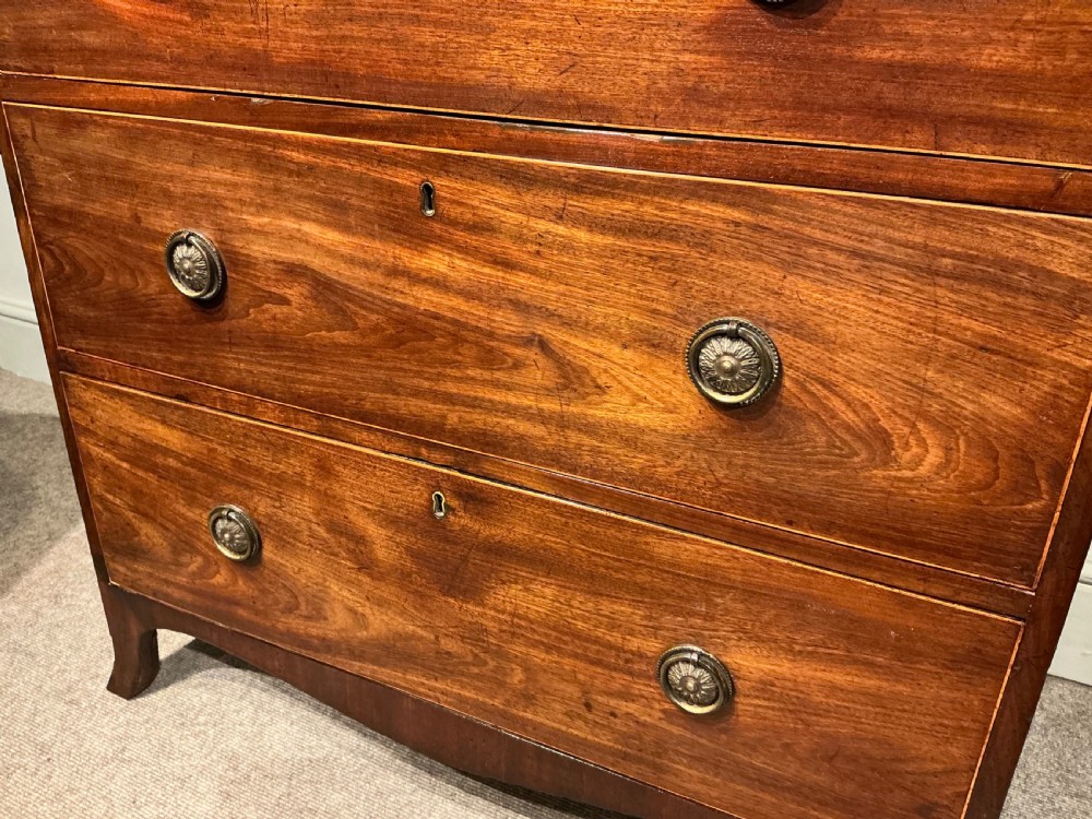 A Georgian mahogany chest of drawers featuring three graduated drawers, a pull-out brushing slide, brass rosette handles, and splayed bracket feet. View II