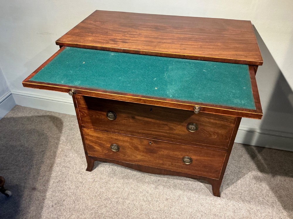 A Georgian mahogany chest of drawers featuring three graduated drawers, a pull-out brushing slide, brass rosette handles, and splayed bracket feet. View VII