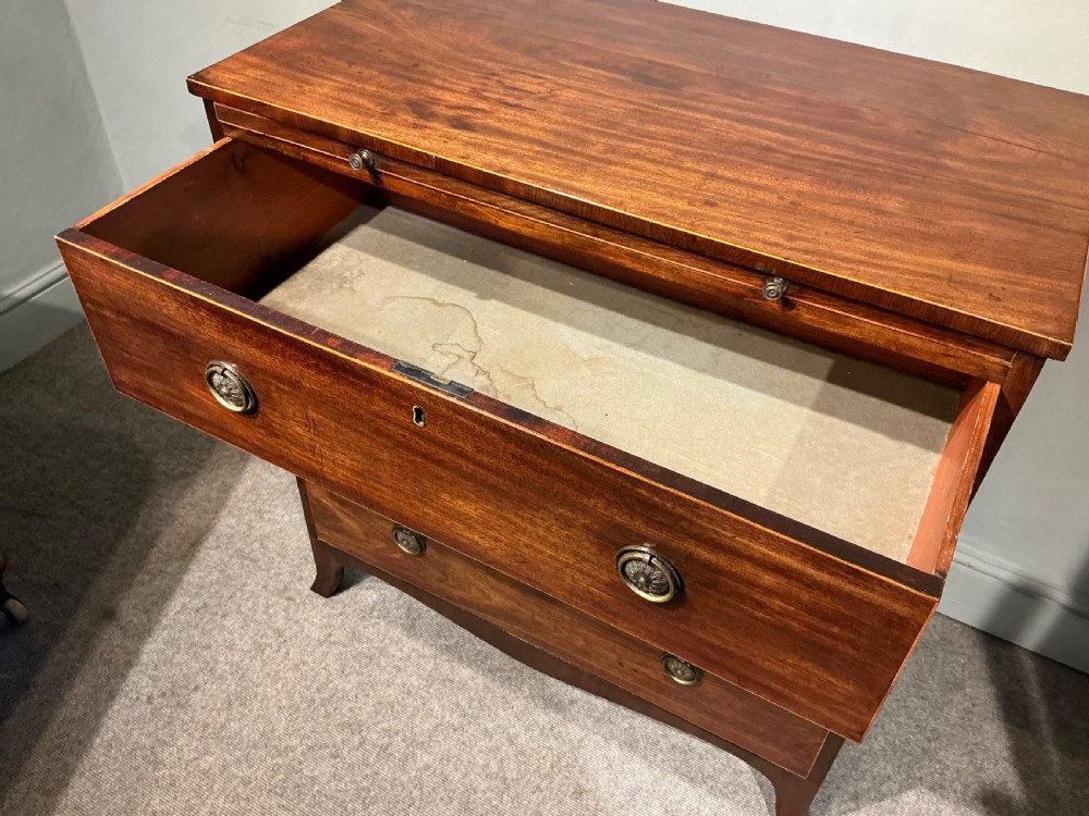 A Georgian mahogany chest of drawers featuring three graduated drawers, a pull-out brushing slide, brass rosette handles, and splayed bracket feet. View VIII