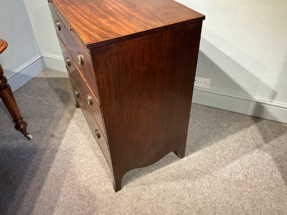 A Georgian mahogany chest of drawers featuring three graduated drawers, a pull-out brushing slide, brass rosette handles, and splayed bracket feet. View IX