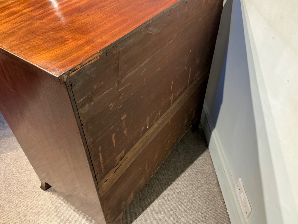 A Georgian mahogany chest of drawers featuring three graduated drawers, a pull-out brushing slide, brass rosette handles, and splayed bracket feet. View X