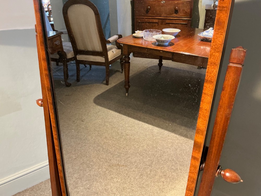 An Edwardian mahogany cheval mirror with a rectangular full-length tilting glass plate supported by two vertical upright posts on splayed legs. View II
