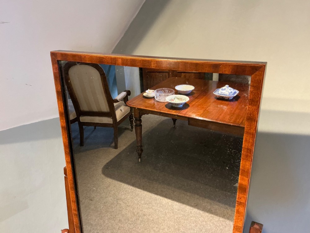 An Edwardian mahogany cheval mirror with a rectangular full-length tilting glass plate supported by two vertical upright posts on splayed legs. View IV