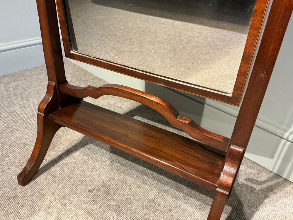 An Edwardian mahogany cheval mirror with a rectangular full-length tilting glass plate supported by two vertical upright posts on splayed legs. View VI