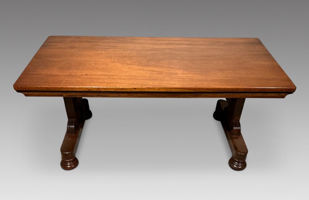A low rectangular mahogany coffee table with a polished warm brown top and carved trestle supports.