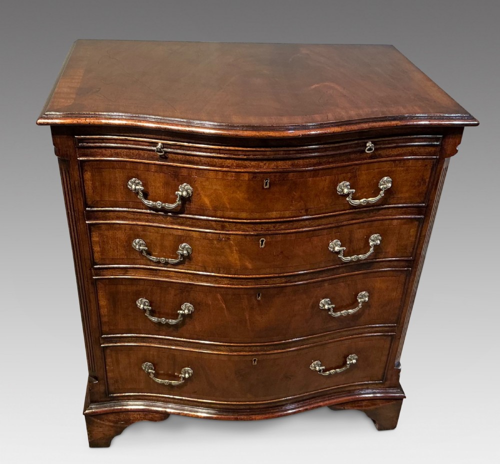 A Georgian mahogany serpentine chest of drawers featuring four graduated drawers with brass swan-neck handles and bracket feet. View II
