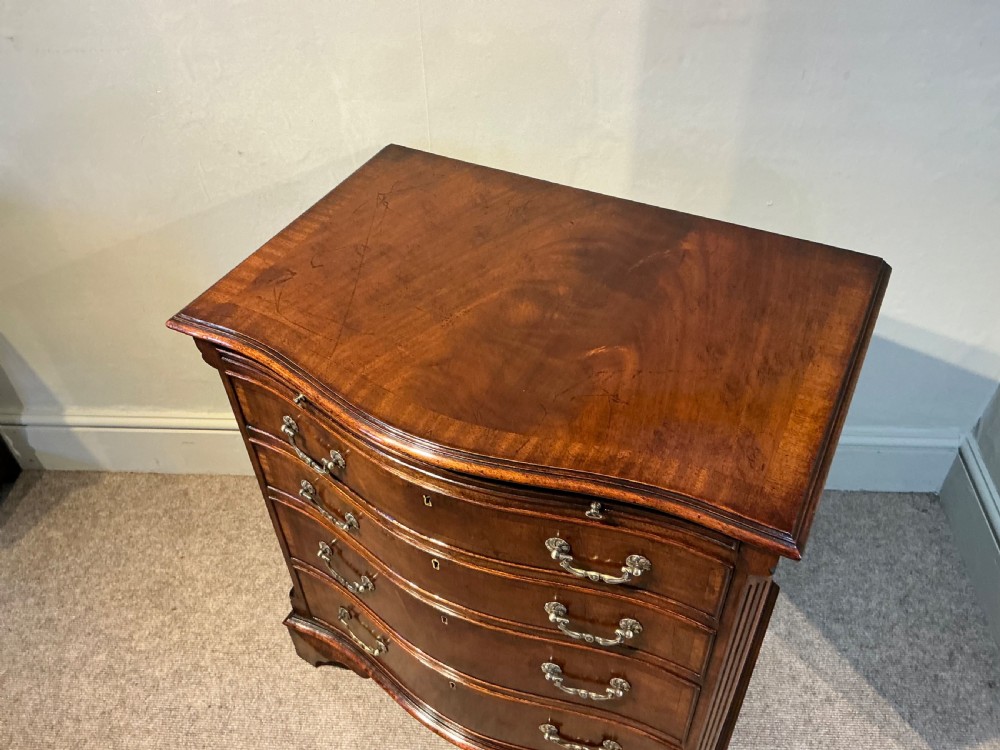 A Georgian mahogany serpentine chest of drawers featuring four graduated drawers with brass swan-neck handles and bracket feet. View III