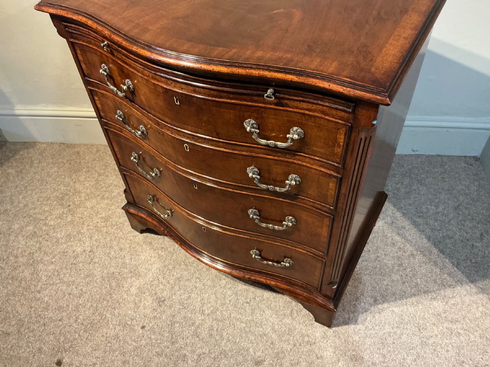 A Georgian mahogany serpentine chest of drawers featuring four graduated drawers with brass swan-neck handles and bracket feet. View IV