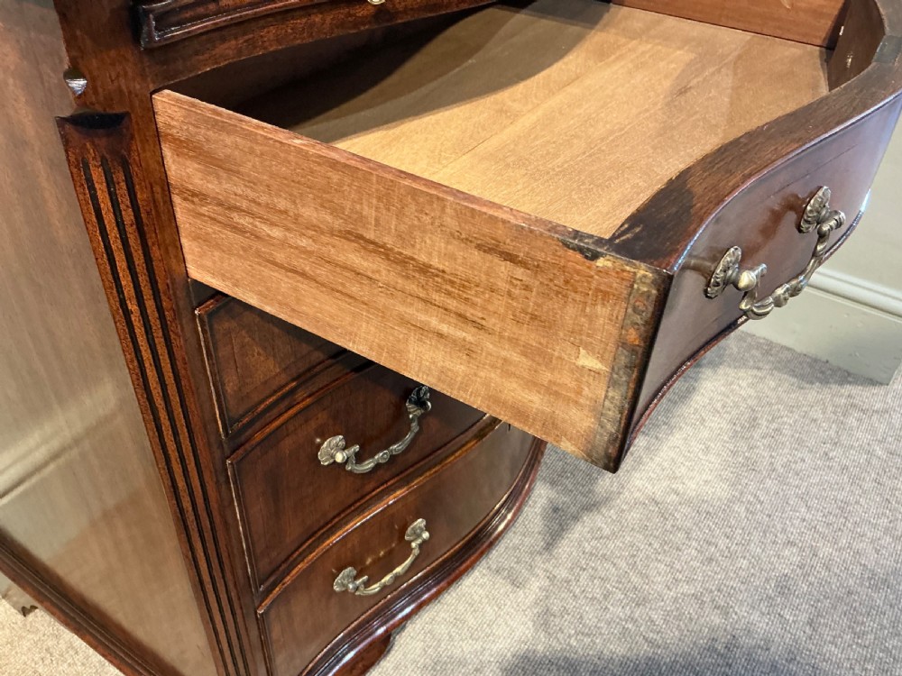 A Georgian mahogany serpentine chest of drawers featuring four graduated drawers with brass swan-neck handles and bracket feet. View VII