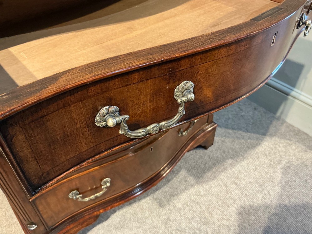 A Georgian mahogany serpentine chest of drawers featuring four graduated drawers with brass swan-neck handles and bracket feet. View VIII