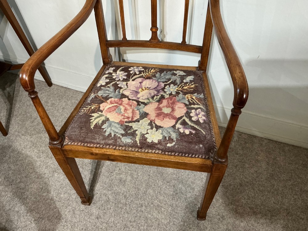 An Edwardian mahogany elbow chair featuring a slatted backrest with central diamond inlay, swept arms, tapered square legs, and a floral needlepoint upholstered seat. View III