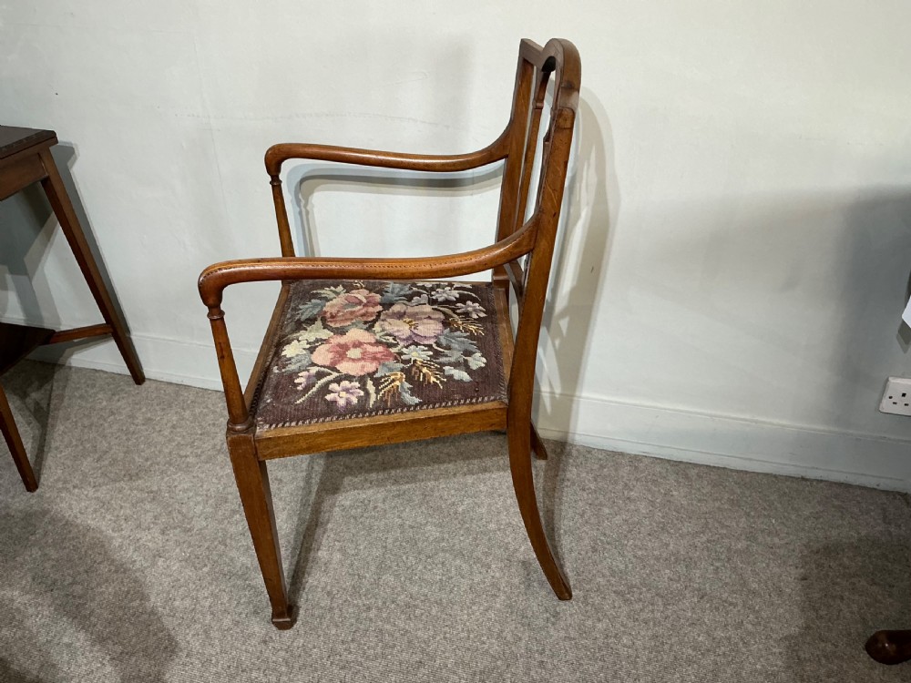 An Edwardian mahogany elbow chair featuring a slatted backrest with central diamond inlay, swept arms, tapered square legs, and a floral needlepoint upholstered seat. View IV