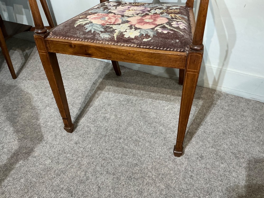 An Edwardian mahogany elbow chair featuring a slatted backrest with central diamond inlay, swept arms, tapered square legs, and a floral needlepoint upholstered seat. View V
