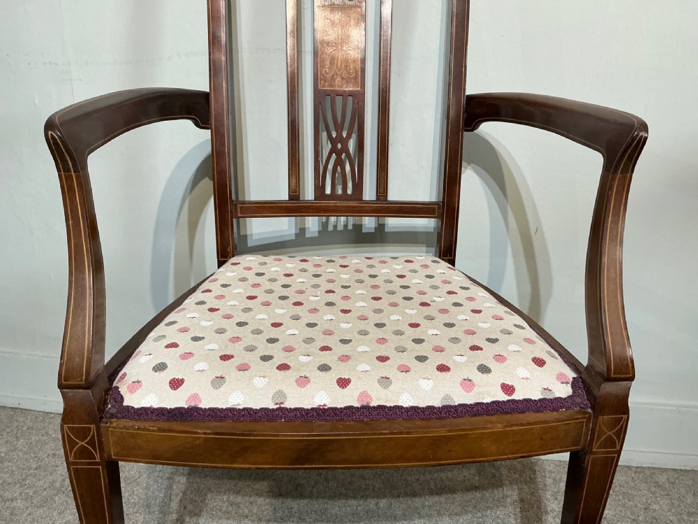 An Edwardian mahogany elbow chair featuring a central pierced splat with satinwood marquetry, swept armrests, and a patterned fabric seat. View II