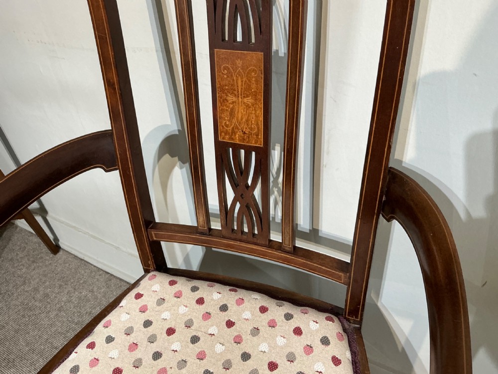 An Edwardian mahogany elbow chair featuring a central pierced splat with satinwood marquetry, swept armrests, and a patterned fabric seat. View III