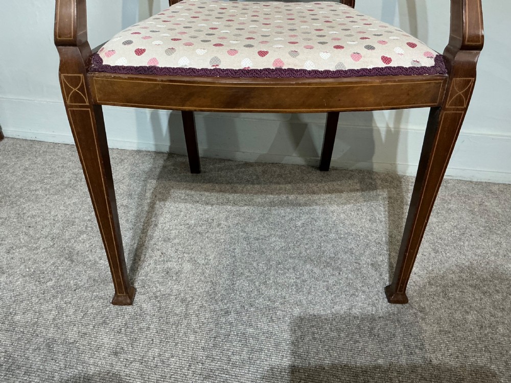 An Edwardian mahogany elbow chair featuring a central pierced splat with satinwood marquetry, swept armrests, and a patterned fabric seat. View IV