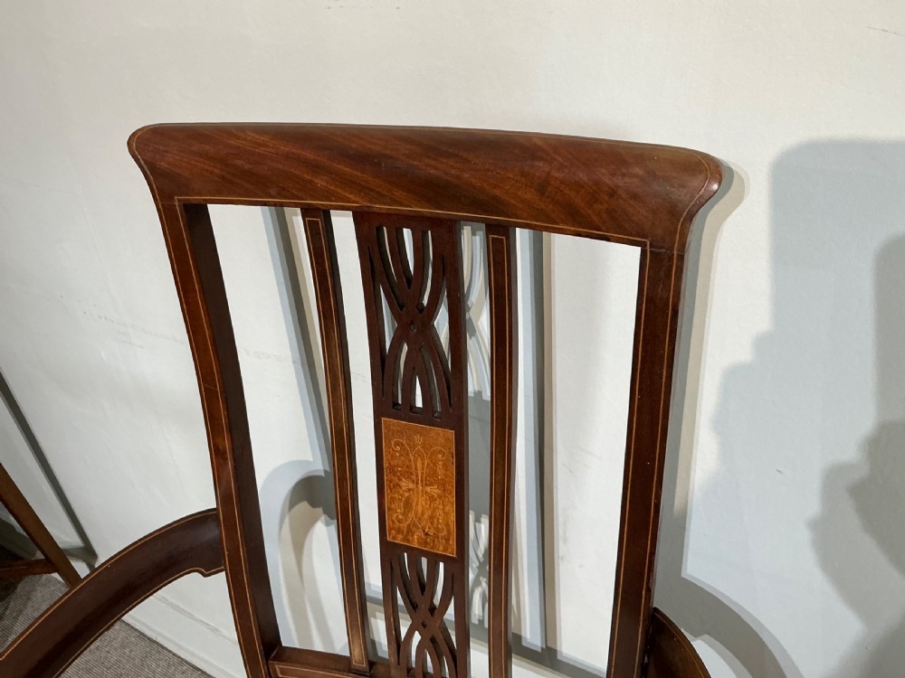 An Edwardian mahogany elbow chair featuring a central pierced splat with satinwood marquetry, swept armrests, and a patterned fabric seat. View V