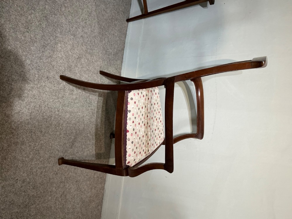 An Edwardian mahogany elbow chair featuring a central pierced splat with satinwood marquetry, swept armrests, and a patterned fabric seat. View VI