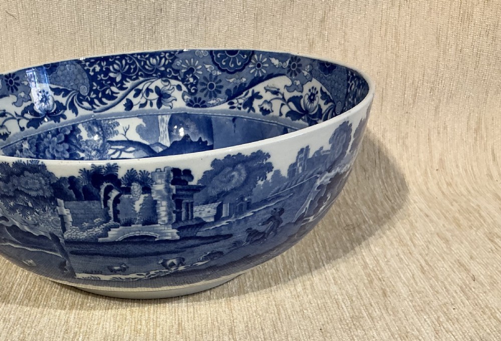 A deep Victorian ceramic bowl decorated inside and out with blue and white underglaze transfer-printed pastoral landscape scenes and an intricate floral border. View II