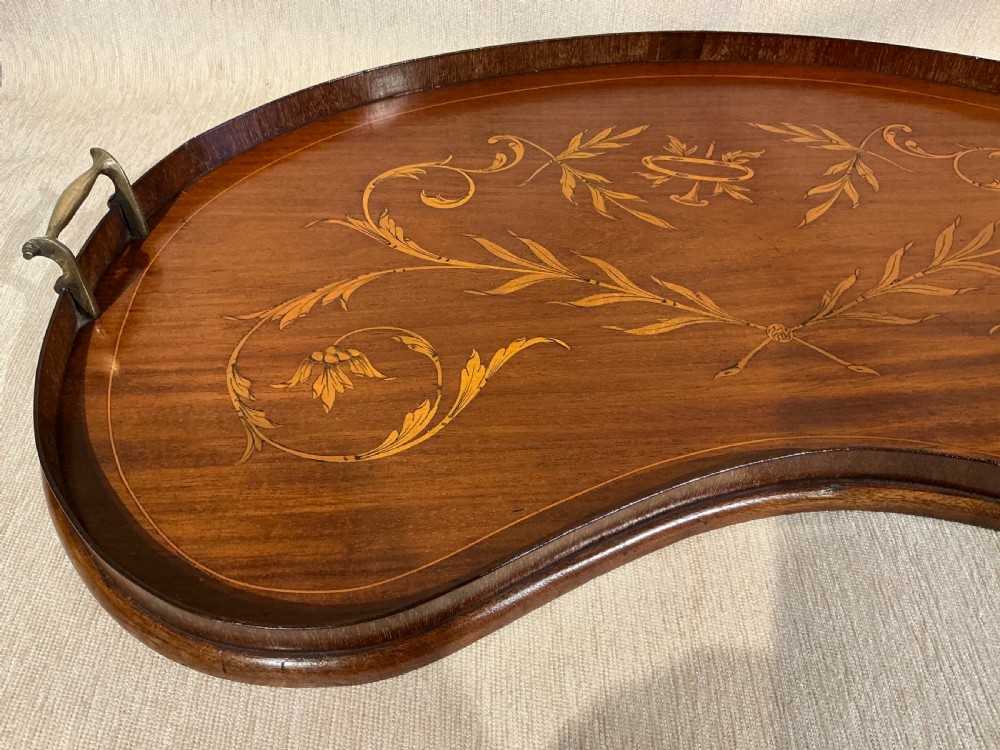 A kidney-shaped mahogany tray featuring inlaid satinwood leaf scrolls and a central urn motif, complete with twin brass handles and a raised gallery edge. View II