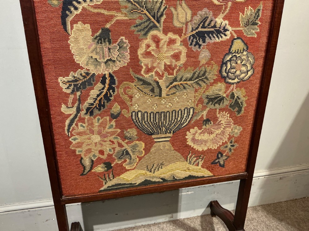 A 19th-century dark wooden fire screen featuring a floral needlepoint panel set on a terracotta background. View III