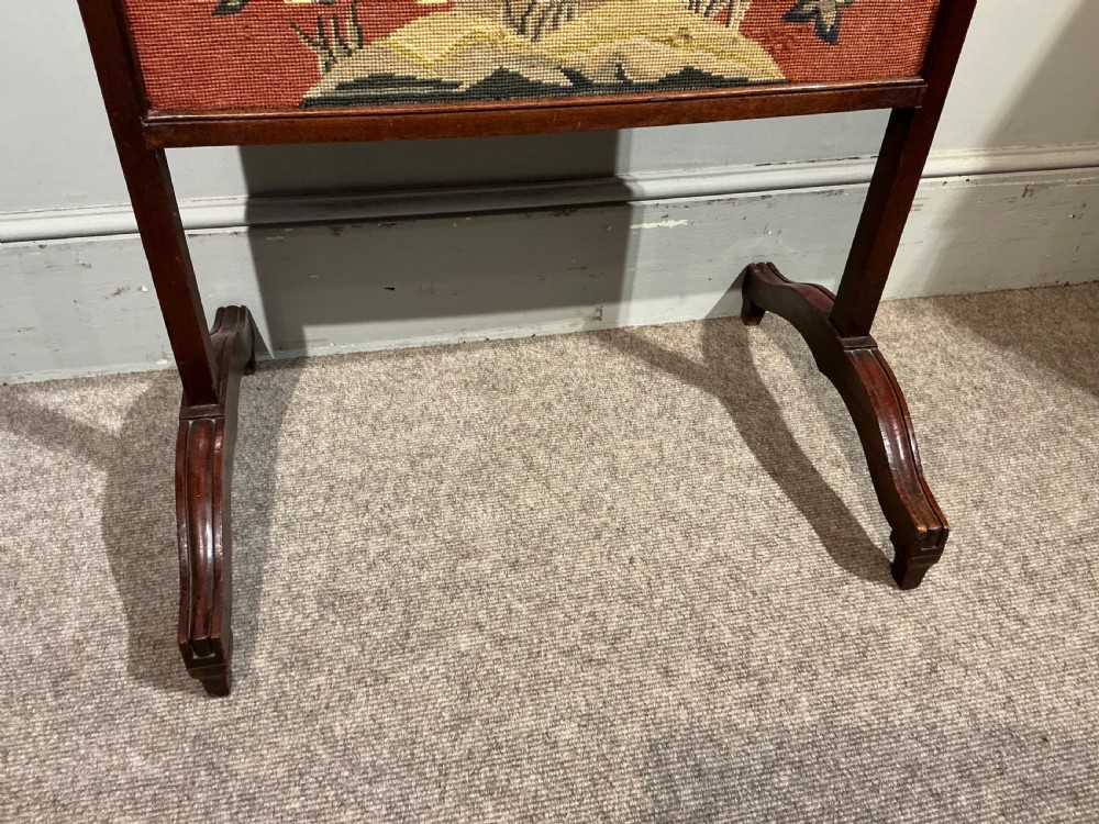 A 19th-century dark wooden fire screen featuring a floral needlepoint panel set on a terracotta background. View IV