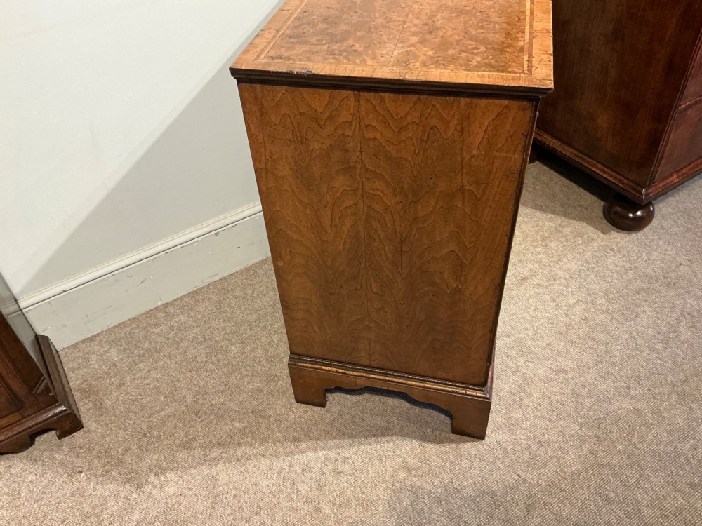 An antique burr walnut chest of drawers featuring two short over three long graduating drawers with brass handles and bracket feet. View VII