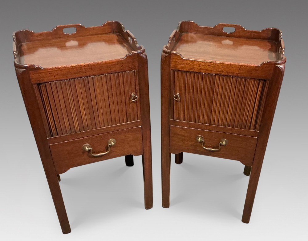 A pair of antique dark mahogany bedside cabinets featuring tray tops with carved handles, slatted tambour sliding doors, single drawers with brass handles, and square legs.