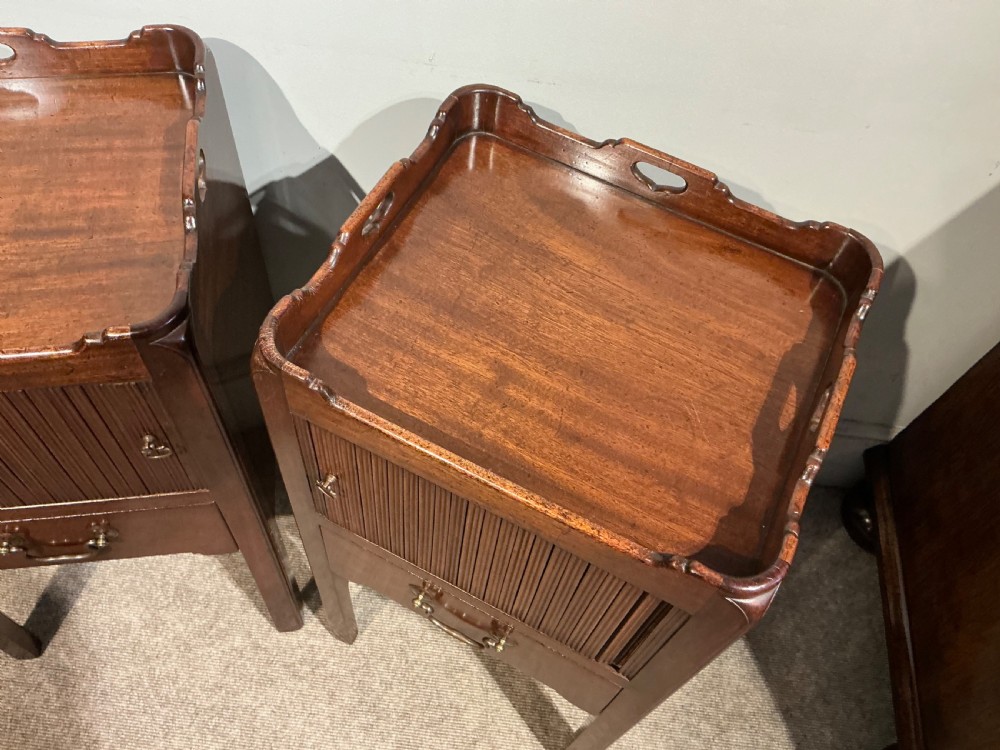 A pair of antique dark mahogany bedside cabinets featuring tray tops with carved handles, slatted tambour sliding doors, single drawers with brass handles, and square legs. View III