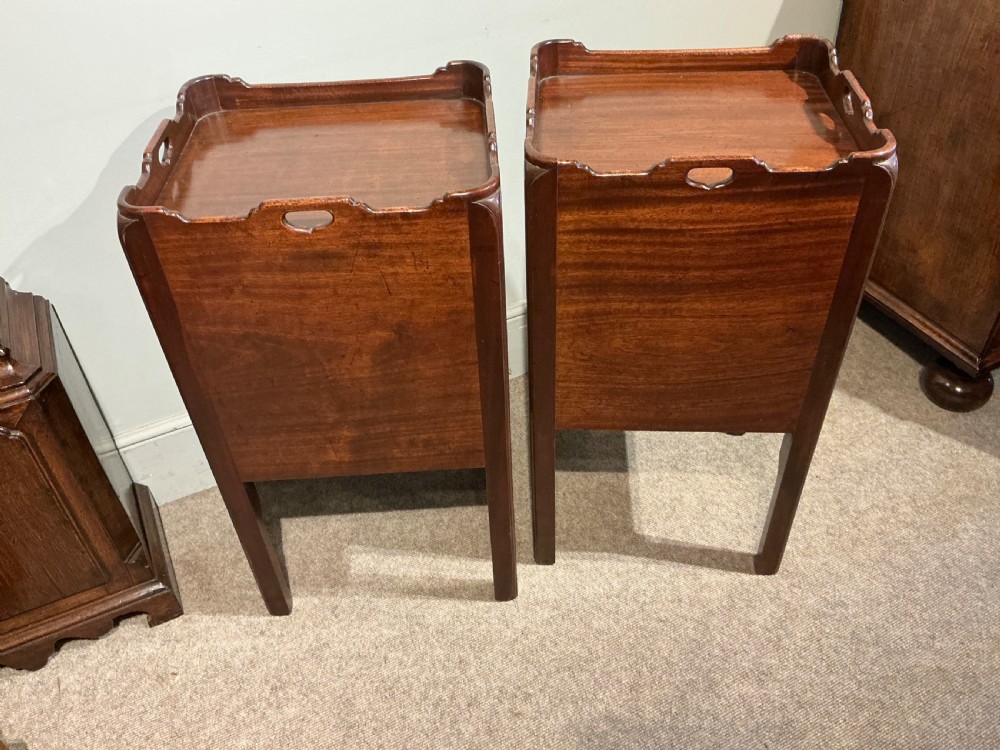 A pair of antique dark mahogany bedside cabinets featuring tray tops with carved handles, slatted tambour sliding doors, single drawers with brass handles, and square legs. View IX