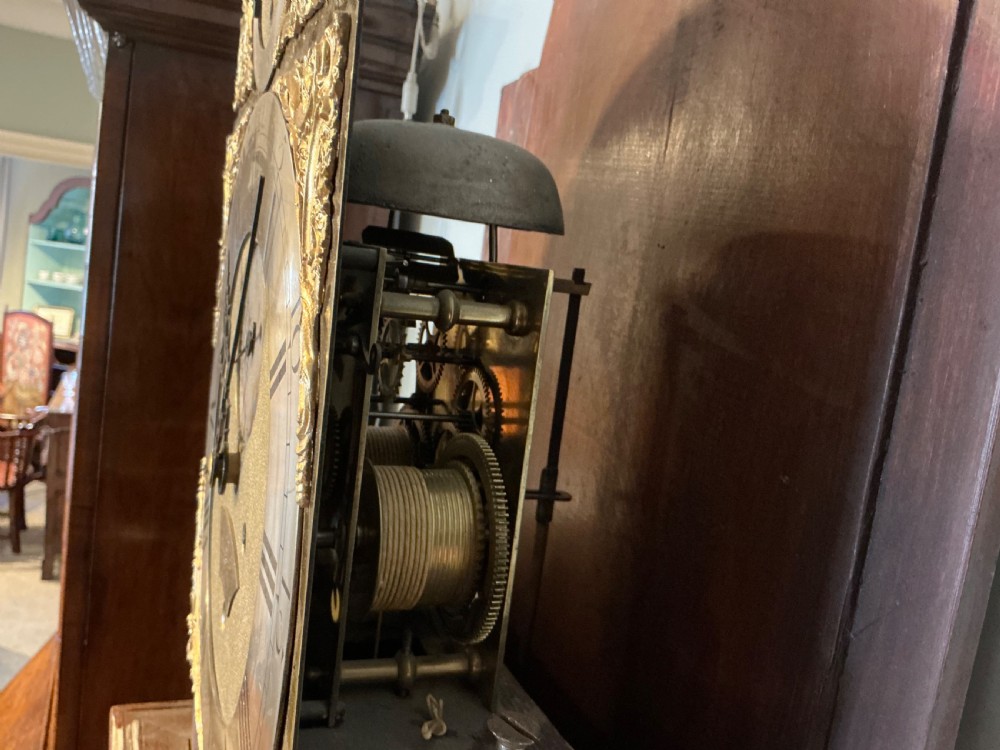 An antique Georgian longcase clock crafted from dark flame mahogany, featuring an arched hood with brass finials and an engraved brass dial. View XII