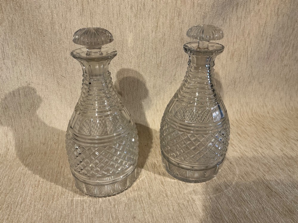A pair of late Georgian clear cut-glass decanters featuring stepped neck rings, diamond pattern bands, and flat mushroom stoppers. View II