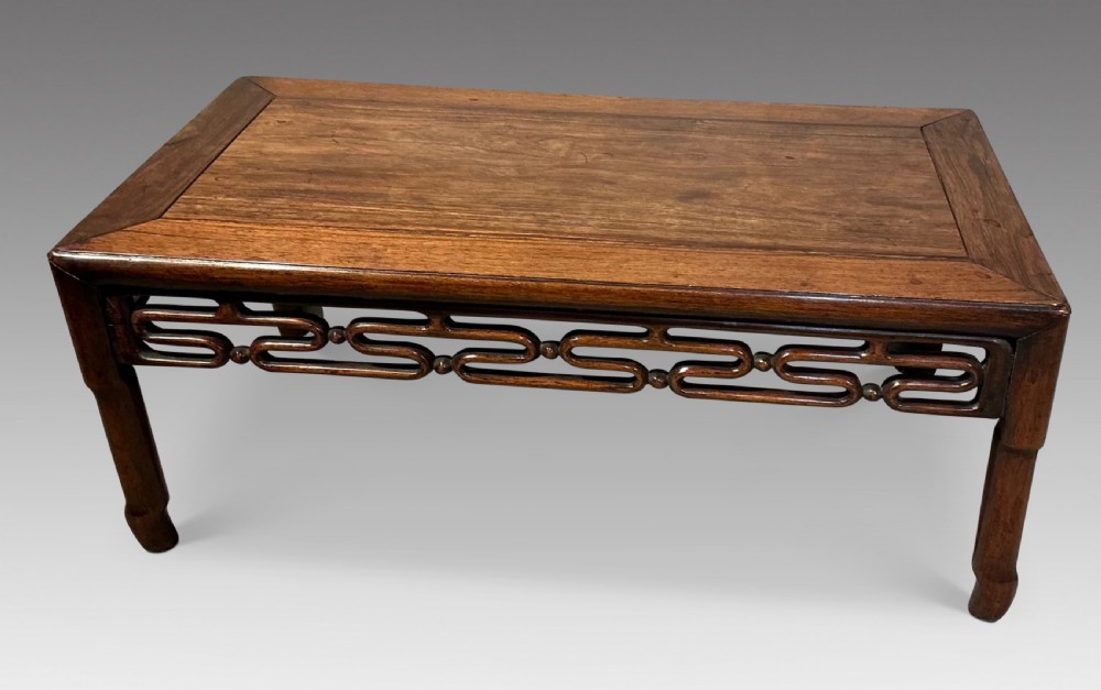 A low rectangular wooden Chinese opium table featuring a carved openwork apron and short inward-curving legs. View III