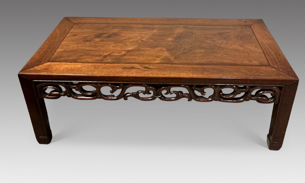 A low rectangular dark hardwood Chinese tea table featuring a mitred frame top, openwork carved scrollwork apron, and straight legs. View II