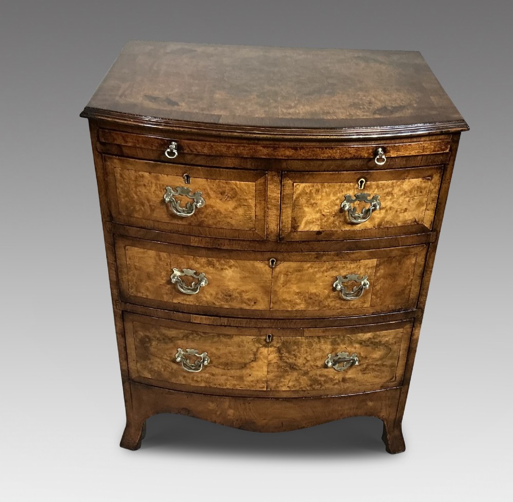 An antique burr walnut bowfront chest of drawers featuring decorative brass handles and a crossbanded top. View II