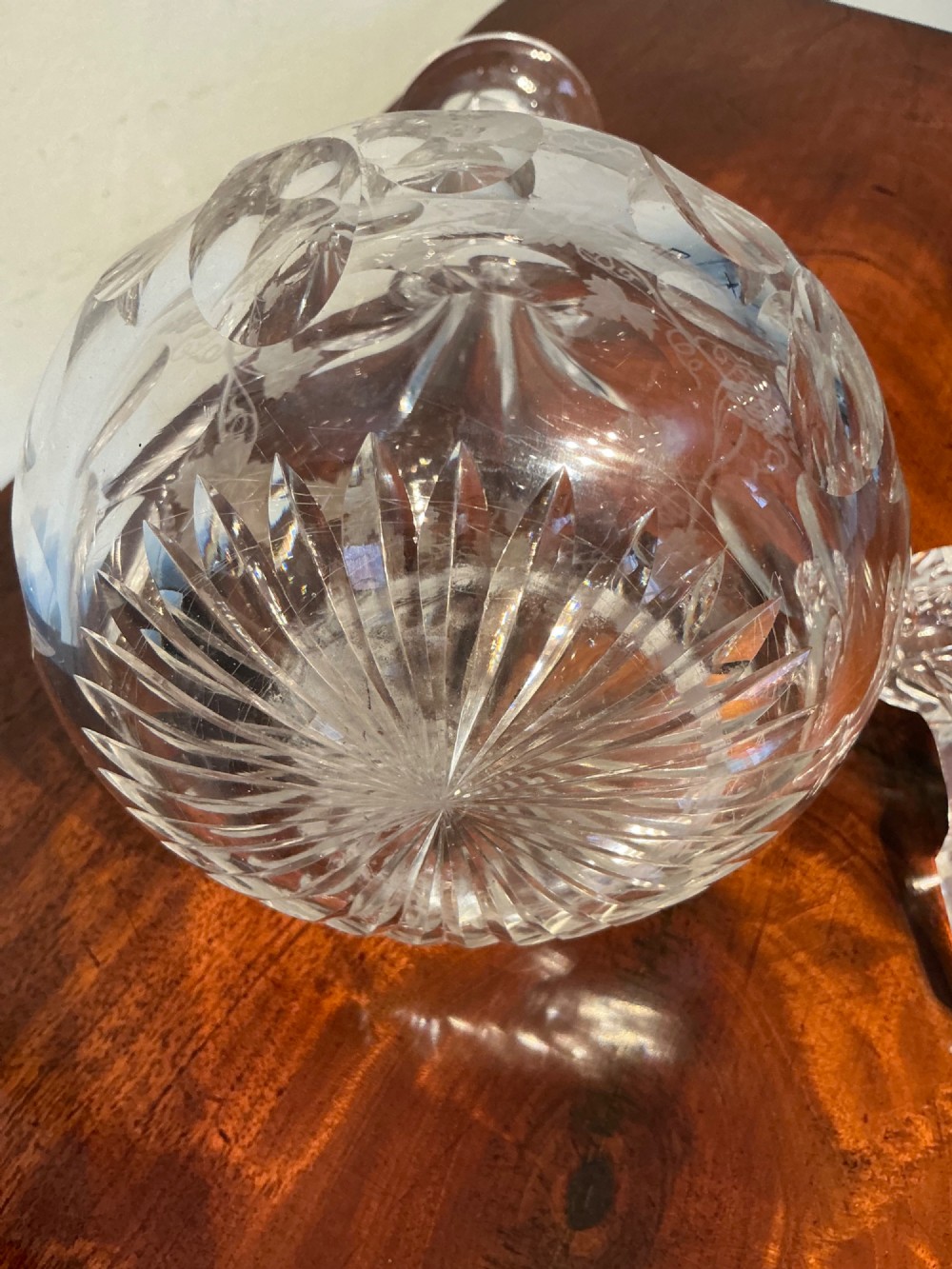 A Victorian clear cut glass decanter featuring etched grapevine motifs, starburst cuttings, a fluted neck, and a faceted glass stopper. View VII