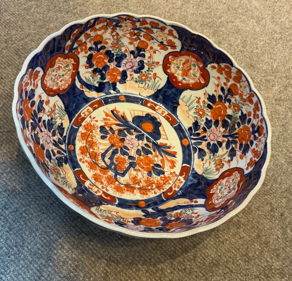 A large hand-painted Japanese Imari porcelain bowl featuring a scalloped lobed rim, floral panels, and underglaze cobalt blue and iron red patterns. View II