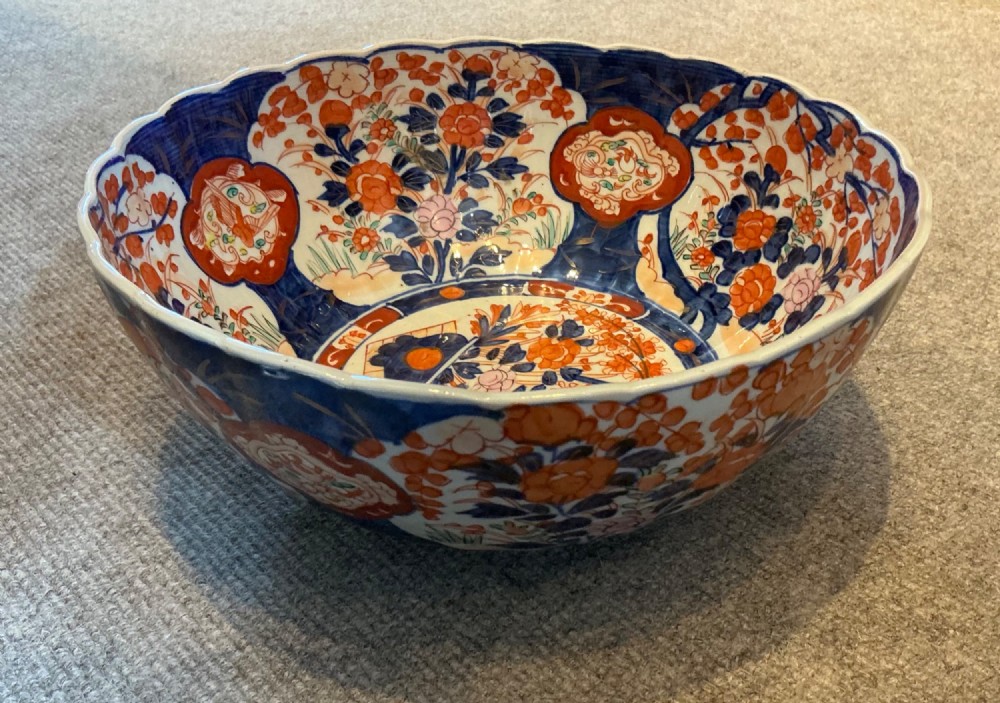 A large hand-painted Japanese Imari porcelain bowl featuring a scalloped lobed rim, floral panels, and underglaze cobalt blue and iron red patterns. View III