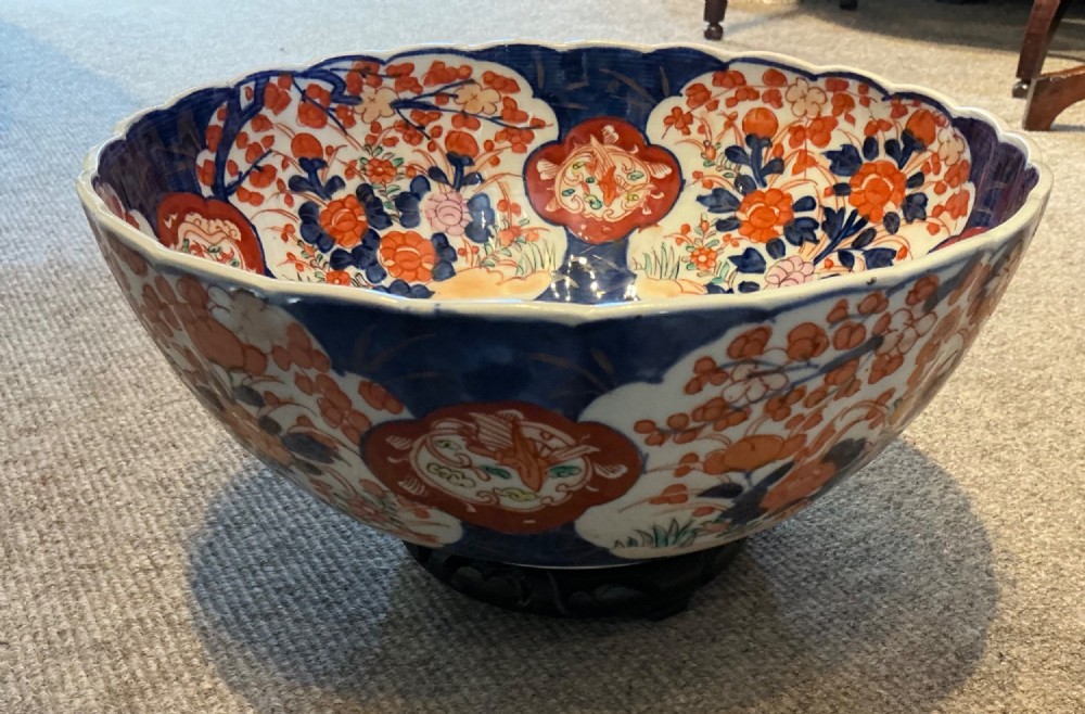 A large hand-painted Japanese Imari porcelain bowl featuring a scalloped lobed rim, floral panels, and underglaze cobalt blue and iron red patterns. View VI
