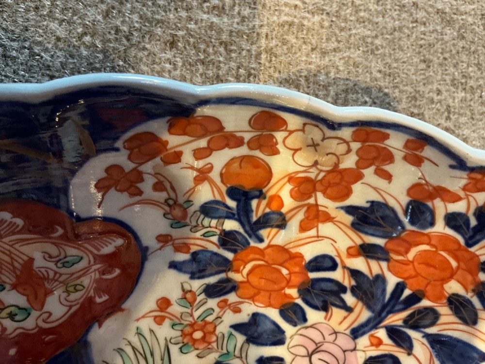 A large hand-painted Japanese Imari porcelain bowl featuring a scalloped lobed rim, floral panels, and underglaze cobalt blue and iron red patterns. View X