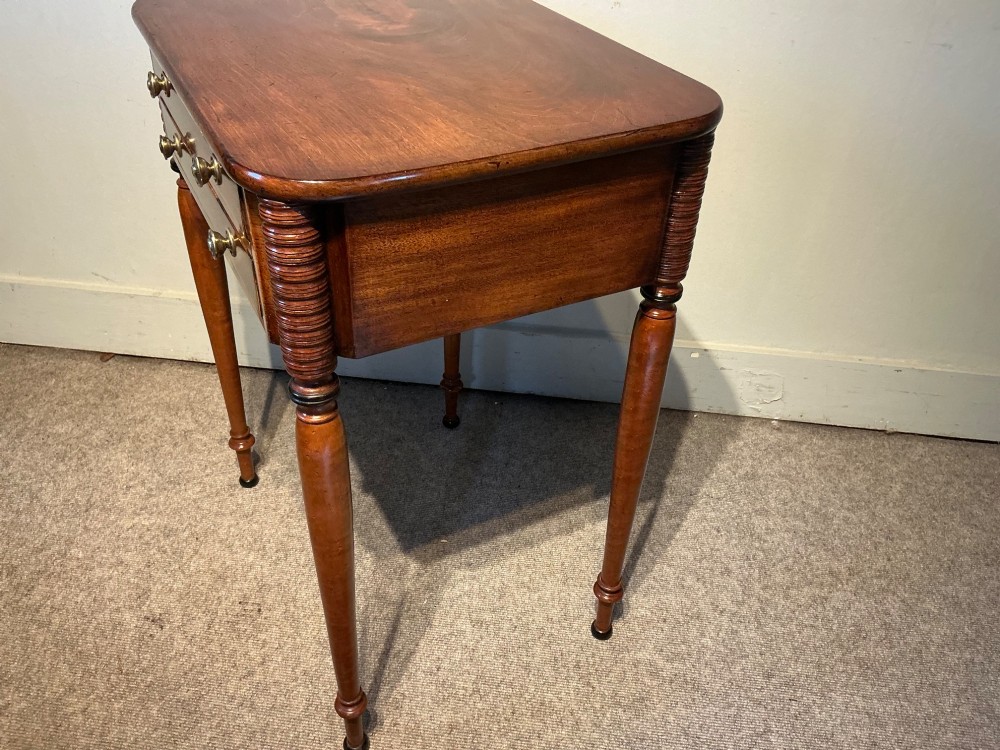 An early nineteenth-century mahogany and maple work table featuring two drawers with brass knobs, reeded upper corner detailing, and turned legs. View VI