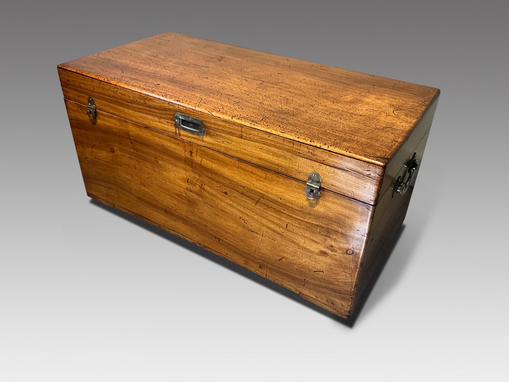 A rectangular antique camphorwood trunk with recessed metal handles and front latches.