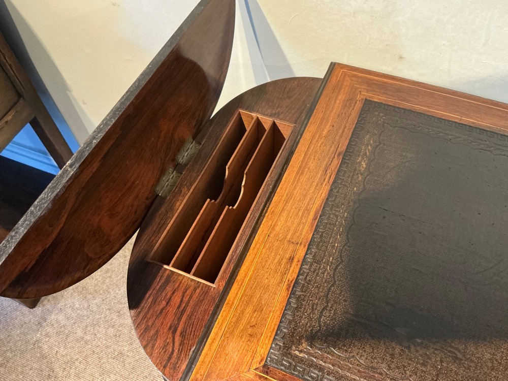 An antique inlaid rosewood writing table featuring a dark leather inset surface, classical urn marquetry, a single drawer, and square tapered legs on brass castors. View V