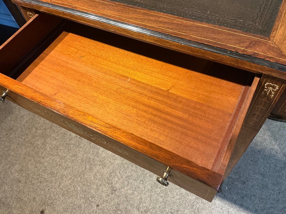 An antique inlaid rosewood writing table featuring a dark leather inset surface, classical urn marquetry, a single drawer, and square tapered legs on brass castors. View XII