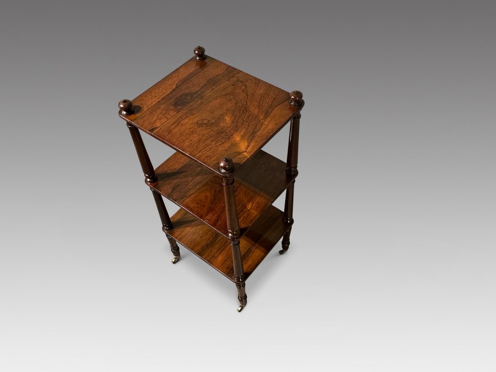 A three-tiered dark rosewood Regency etagere featuring turned supports, corner finials, and brass castors. View II