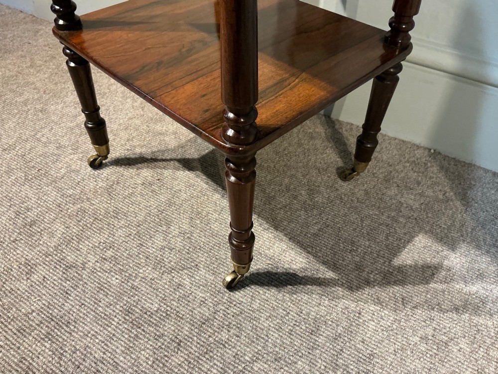 A three-tiered dark rosewood Regency etagere featuring turned supports, corner finials, and brass castors. View VII