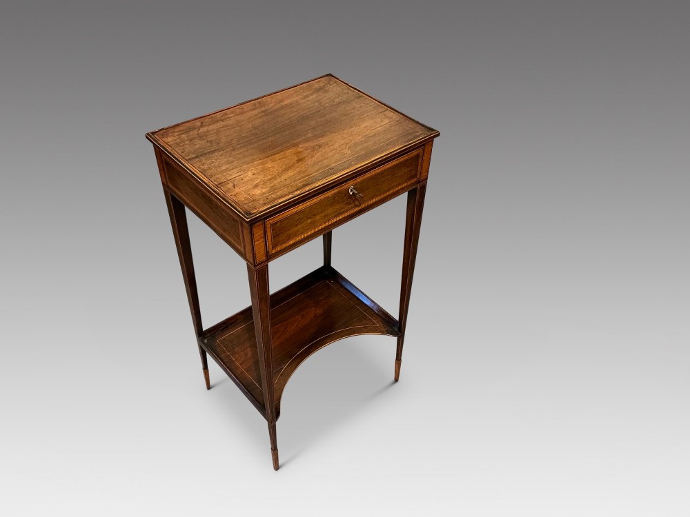 A late Georgian Sheraton mahogany work table featuring satinwood crossbanding, a single drawer, tapered square legs, and a concave lower undertier. View II