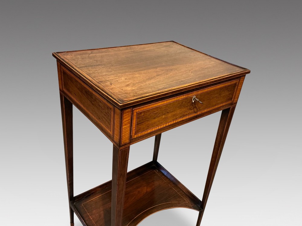 A late Georgian Sheraton mahogany work table featuring satinwood crossbanding, a single drawer, tapered square legs, and a concave lower undertier. View IV