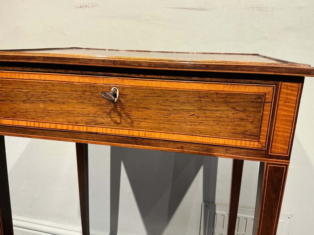 A late Georgian Sheraton mahogany work table featuring satinwood crossbanding, a single drawer, tapered square legs, and a concave lower undertier. View XI